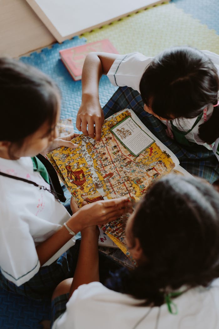 Three children reading a colorful book together, promoting learning and education.