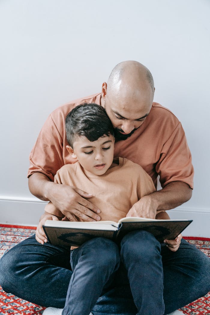A father and son enjoying a quiet moment reading together inside their home.